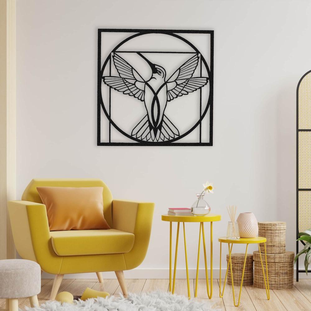 Black metal hummingbird wall art with a circular geometric design displayed above a cozy yellow armchair and matching yellow side tables in a stylish, modern living space.