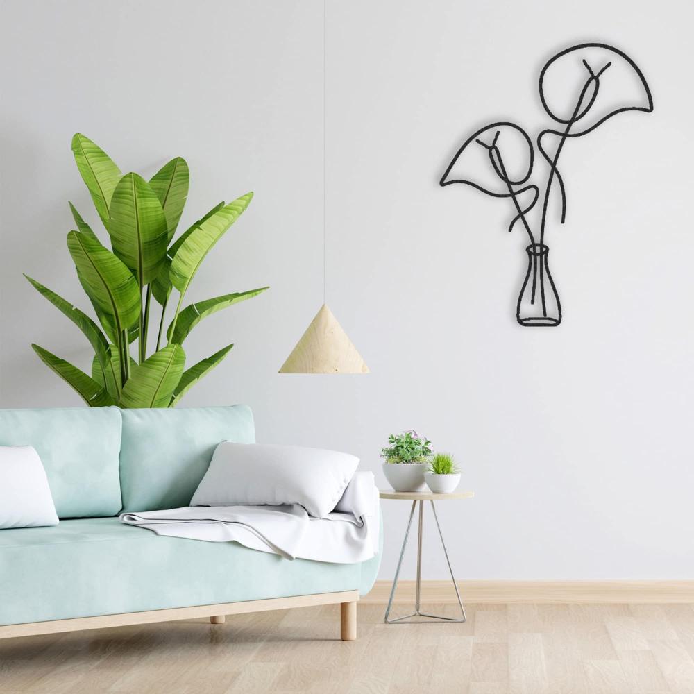 Black metal wall art featuring abstract leaves in a vase on a white wall, complemented by a light green sofa with white pillows. A modern triangular pendant light hangs above, and a side table with small potted plants adds a touch of greenery alongside a tall banana plant for a fresh, serene living room ambiance.