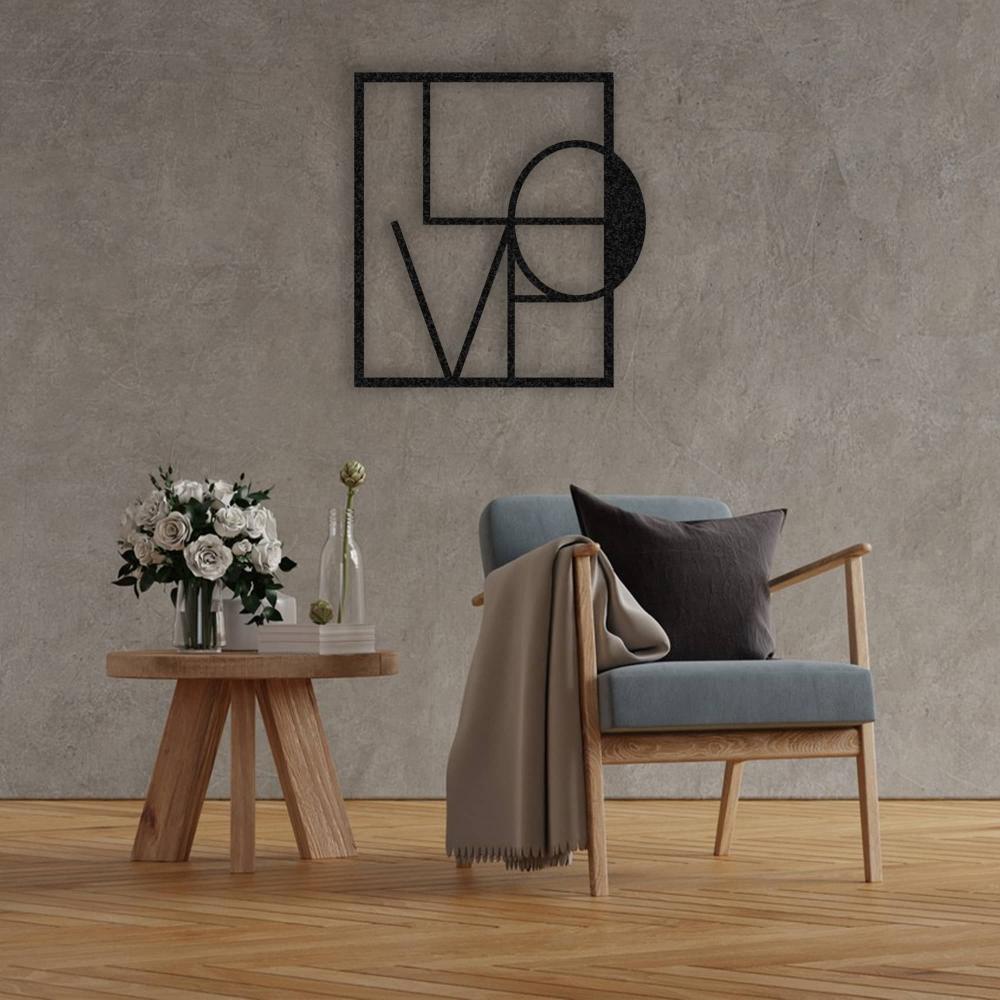 A stylish living room featuring a black metal "LOVE" wall art with geometric shapes, mounted on a textured grey wall above a cozy chair and side table with flowers.