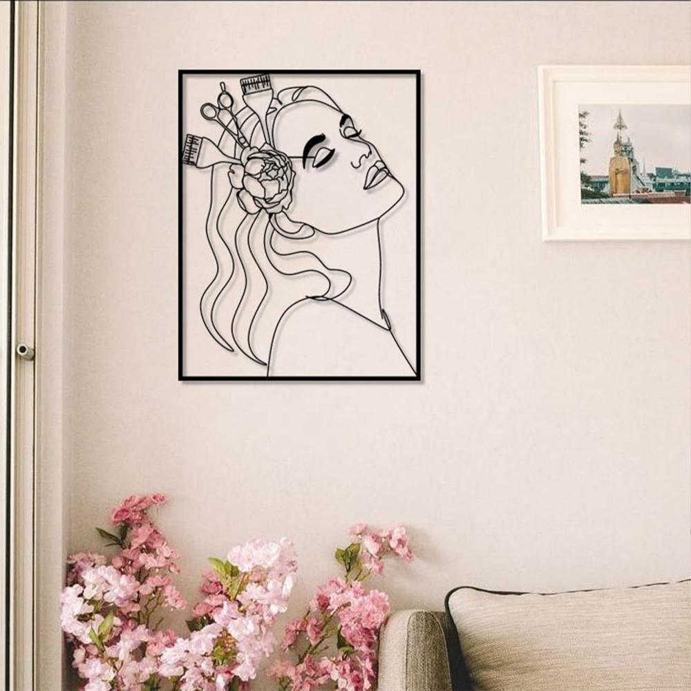 A feminine space with black metal wall art of a woman’s profile, mounted on a light wall above a sofa surrounded by pink floral accents.