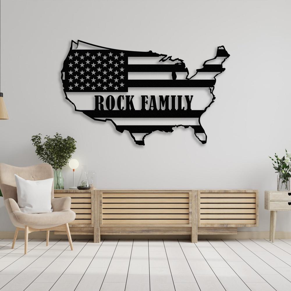 USA map black metal wall art with "Rock Family" text, mounted above a light wooden console table and armchair in a modern living room setting.