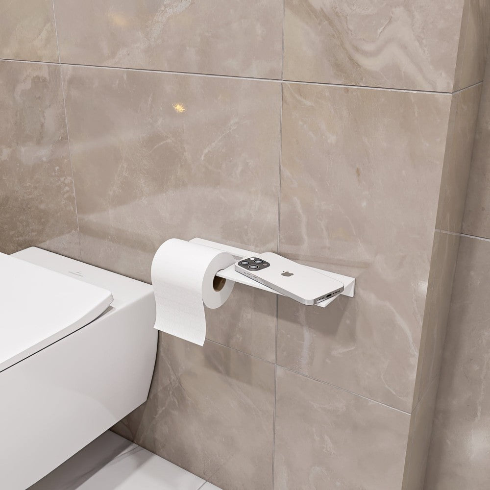 A white multifunctional bathroom shelf with a toilet paper holder, mounted on beige marble tiles, featuring a smartphone on the shelf and a roll of toilet paper hanging below.