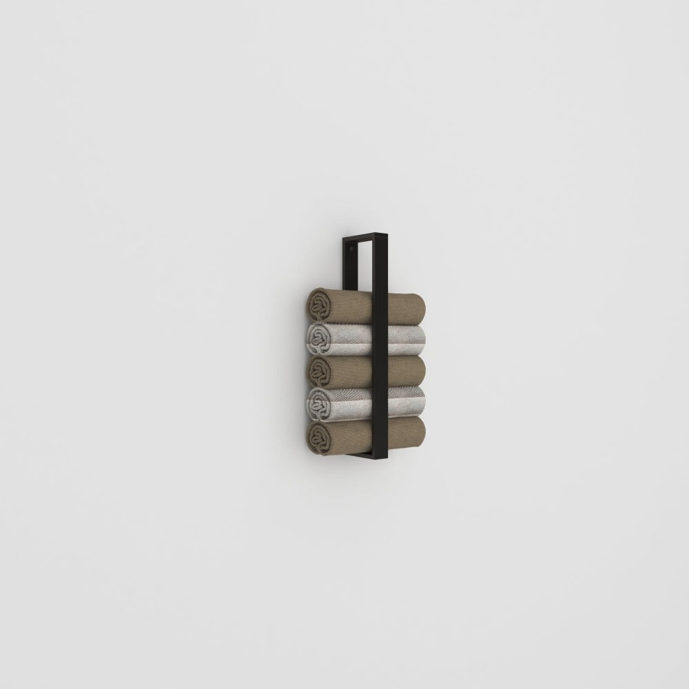 A sleek black towel holder mounted on a plain white wall, neatly stacked with rolled towels in neutral tones, showcasing its simple and functional design.
