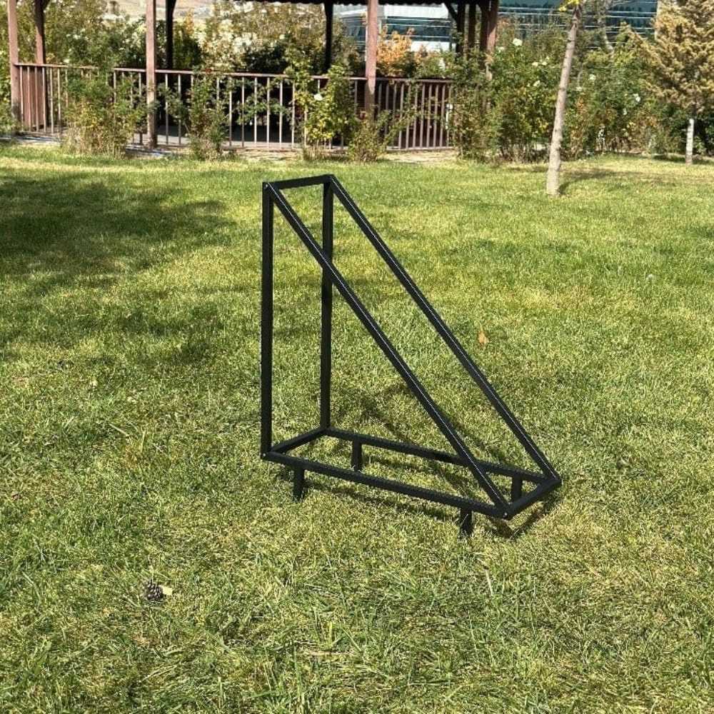 An empty black triangular metal wood rack, placed outdoors on a grassy field, showcasing its sturdy and minimalistic construction under natural light. triangle firewood rack, modern log holder for fireplace