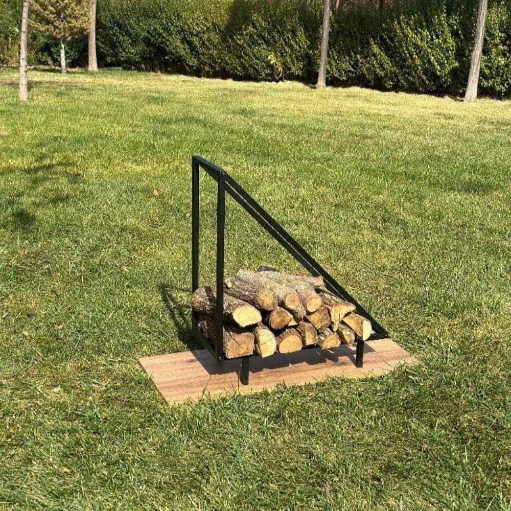 A black metal wood rack with a triangular design placed outdoors on a wooden base, holding logs of firewood, blending with the natural grassy background. triangle firewood rack, modern log holder for fireplace