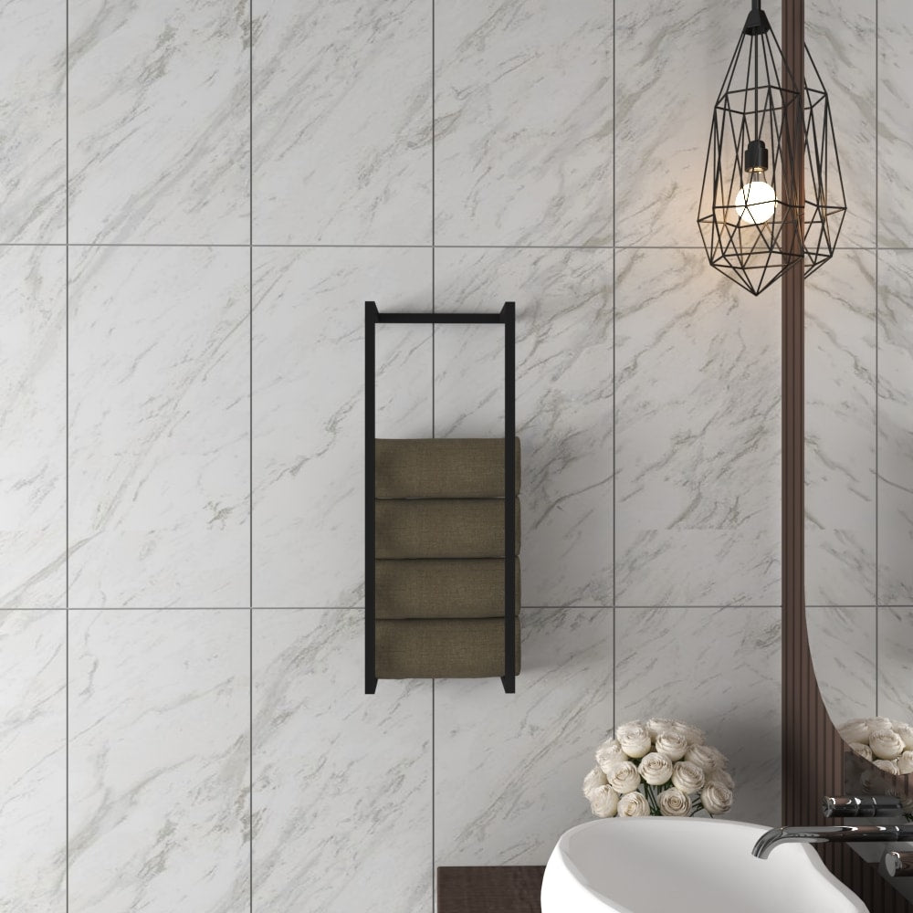 Modern wall-mounted towel and blanket storage rack in black, holding rolled towels, displayed in a minimalist bathroom setting with white marble walls and an industrial-style pendant light.