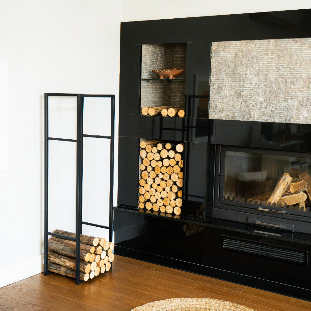 Modern black fireplace with stacked logs and a small shelf in a room. modern log holder for fireplace, minimalist firewood rack with shelf