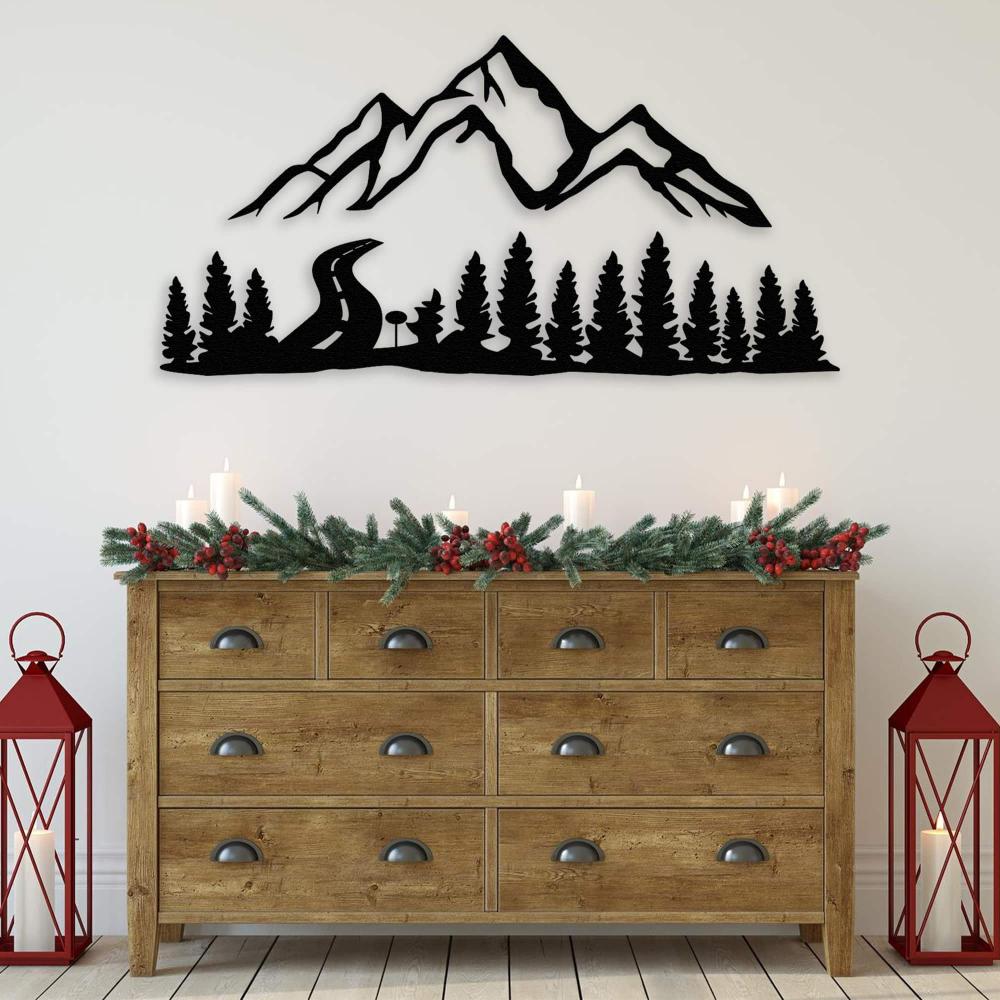 Black mountain and forest metal wall art displayed above a rustic wooden dresser adorned with festive greenery, red berries, and candles, flanked by red lanterns for a cozy holiday-themed decor setting.