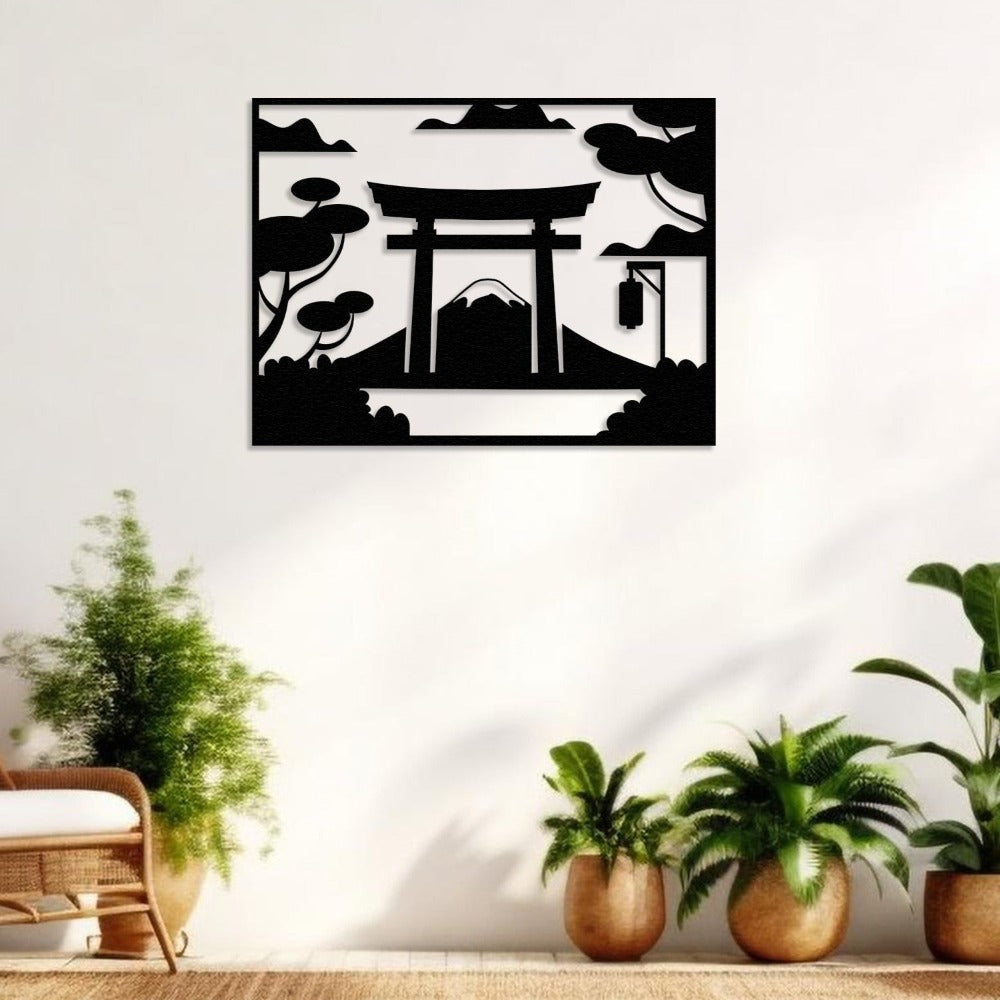 A black metal wall art piece featuring a Japanese Torii gate with Mount Fuji in the background, surrounded by trees and clouds. Displayed in a room with plants and natural light, creating a serene and elegant ambiance.