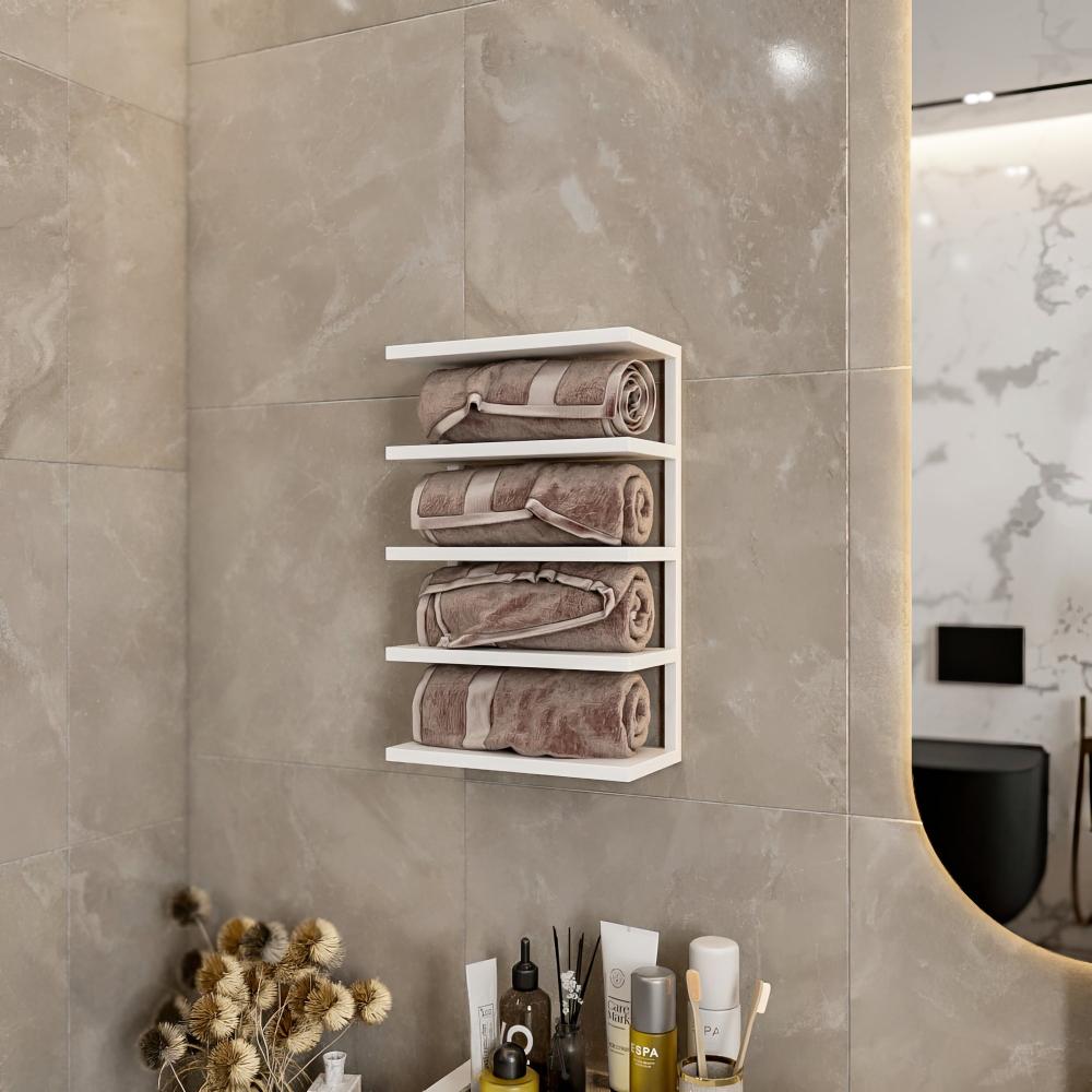 White wall-mounted towel rack in a modern bathroom setting, holding neatly rolled beige towels. The sleek design complements the neutral-toned tile wall and minimalistic decor. Below the rack, a collection of spa essentials and dried flowers add a touch of elegance and functionality