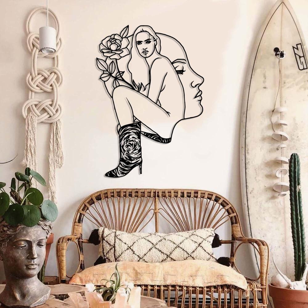 Boho-style living room with rattan furniture and a unique modern metal wall art depicting a woman's face and body with a rose and high boots.
