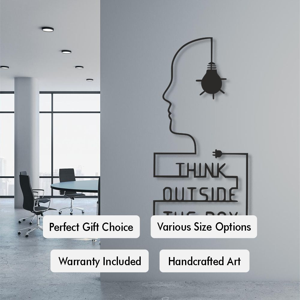 Wall art with a silhouette of a head and light bulb, featuring text 'Think Outside the Box', in an office setting.
