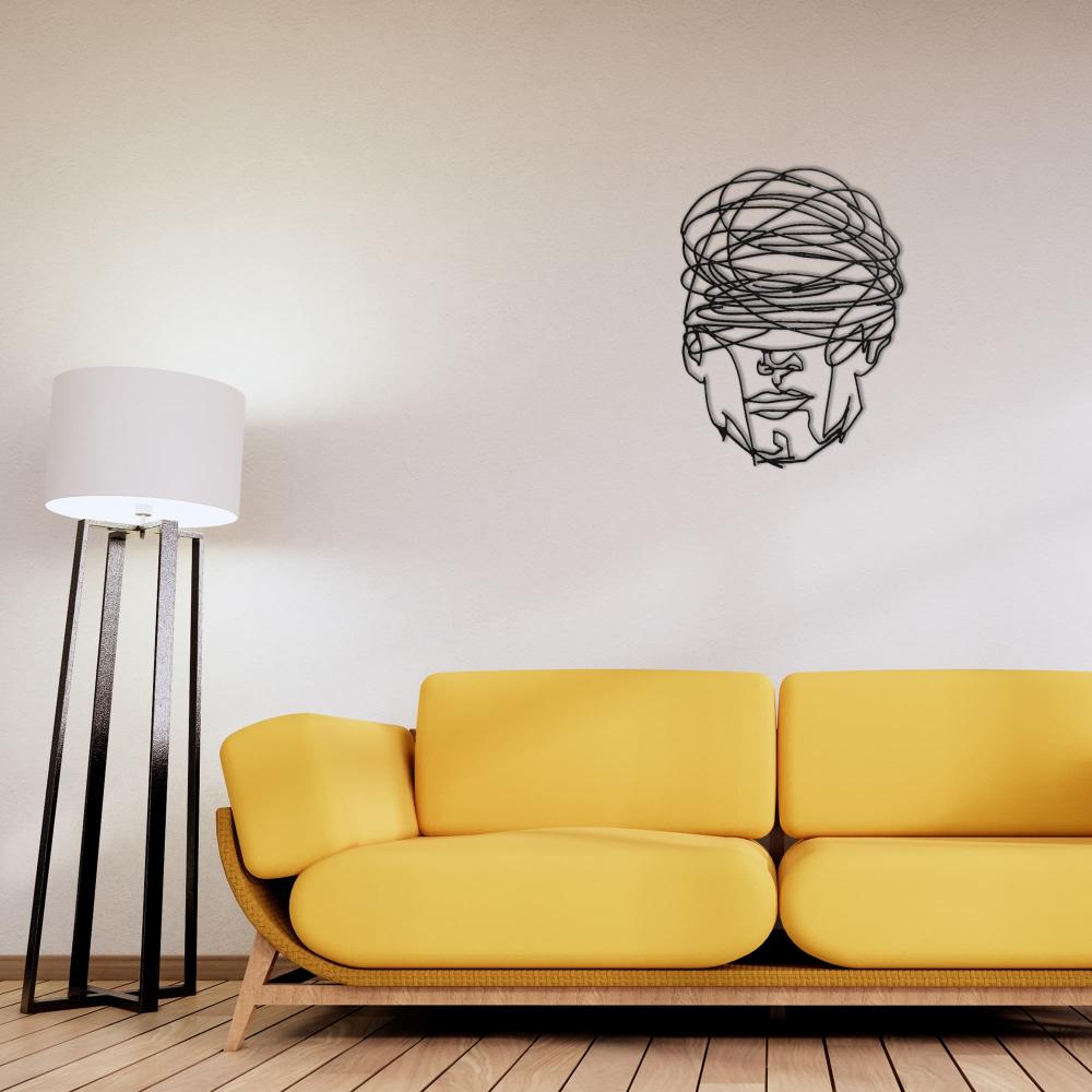 Minimalist living room featuring "Overthinking Man" black metal wall art mounted on a beige wall above a modern yellow sofa, paired with a sleek black floor lamp and wooden flooring for a warm, contemporary aesthetic.