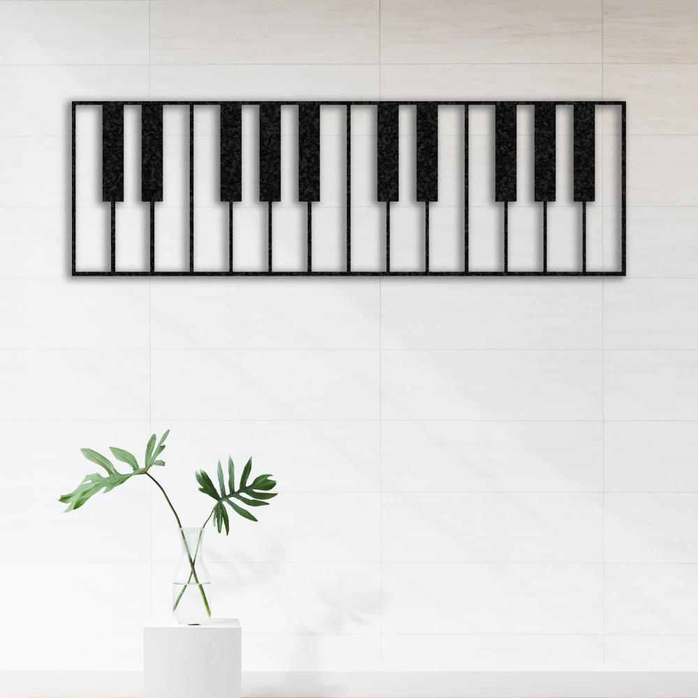 Piano keys-themed metal wall art in a black design, mounted on a tiled white wall. The simple and elegant decor features a single green leaf in a glass vase placed on a white pedestal, creating a minimalist aesthetic.