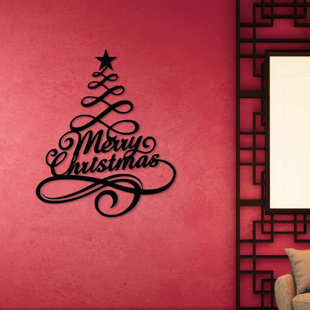 Black metal Christmas tree wall art with "Merry Christmas" elegantly scripted, mounted on a vibrant pink wall next to a modern geometric frame, adding festive charm to a contemporary setting.