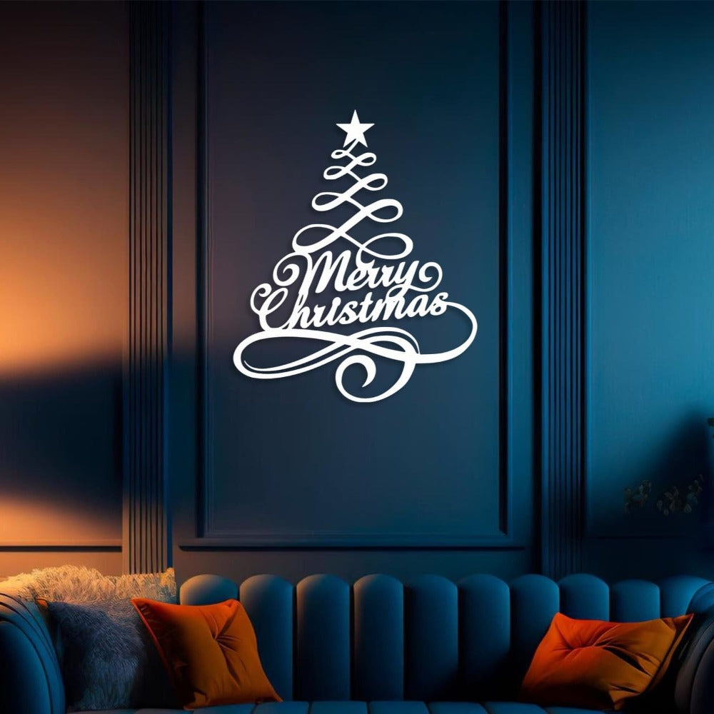 White metal Christmas tree wall art featuring "Merry Christmas" in elegant script, mounted on a dark blue wall above a cozy sofa with vibrant pillows, creating a sophisticated and festive holiday atmosphere.