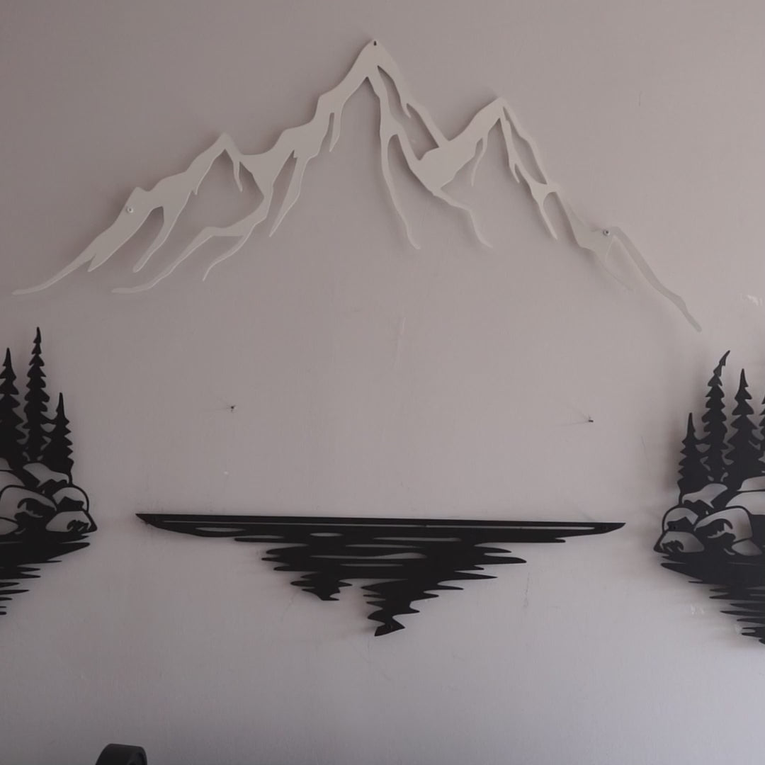 Nature-themed metal wall art depicting a mountain in the center with trees and rocks on either side, reflecting in a lake below