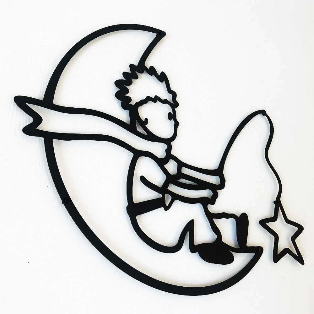 Black metal wall art depicting a charming boy sitting on a crescent moon, holding a star, adding a whimsical and artistic touch to any space.