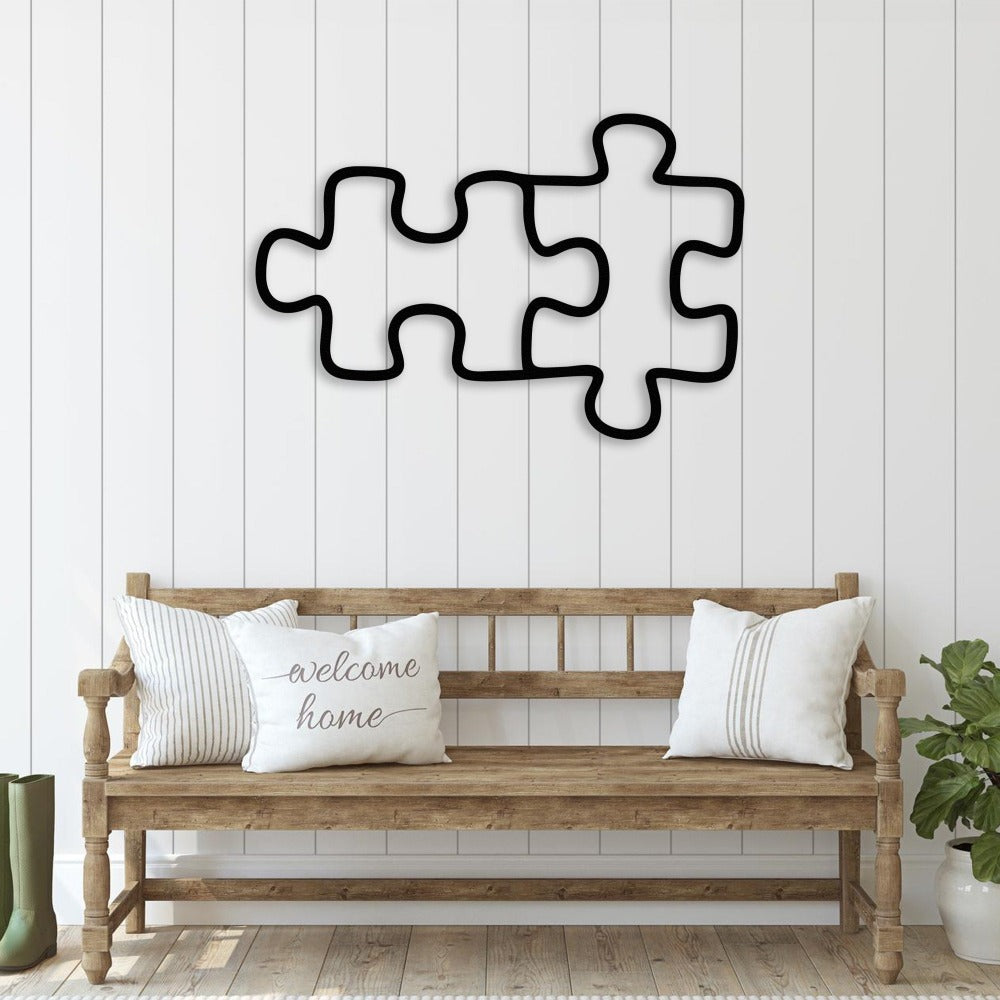 Two black puzzle pieces wall decor displayed above a rustic wooden bench with white pillows, enhancing the farmhouse aesthetic.