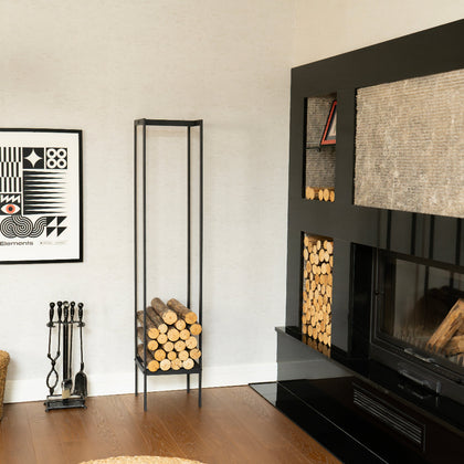 Modern living room with a black fireplace, firewood stand, and decorative items. indoor firewood rack, tall firewood storage rack