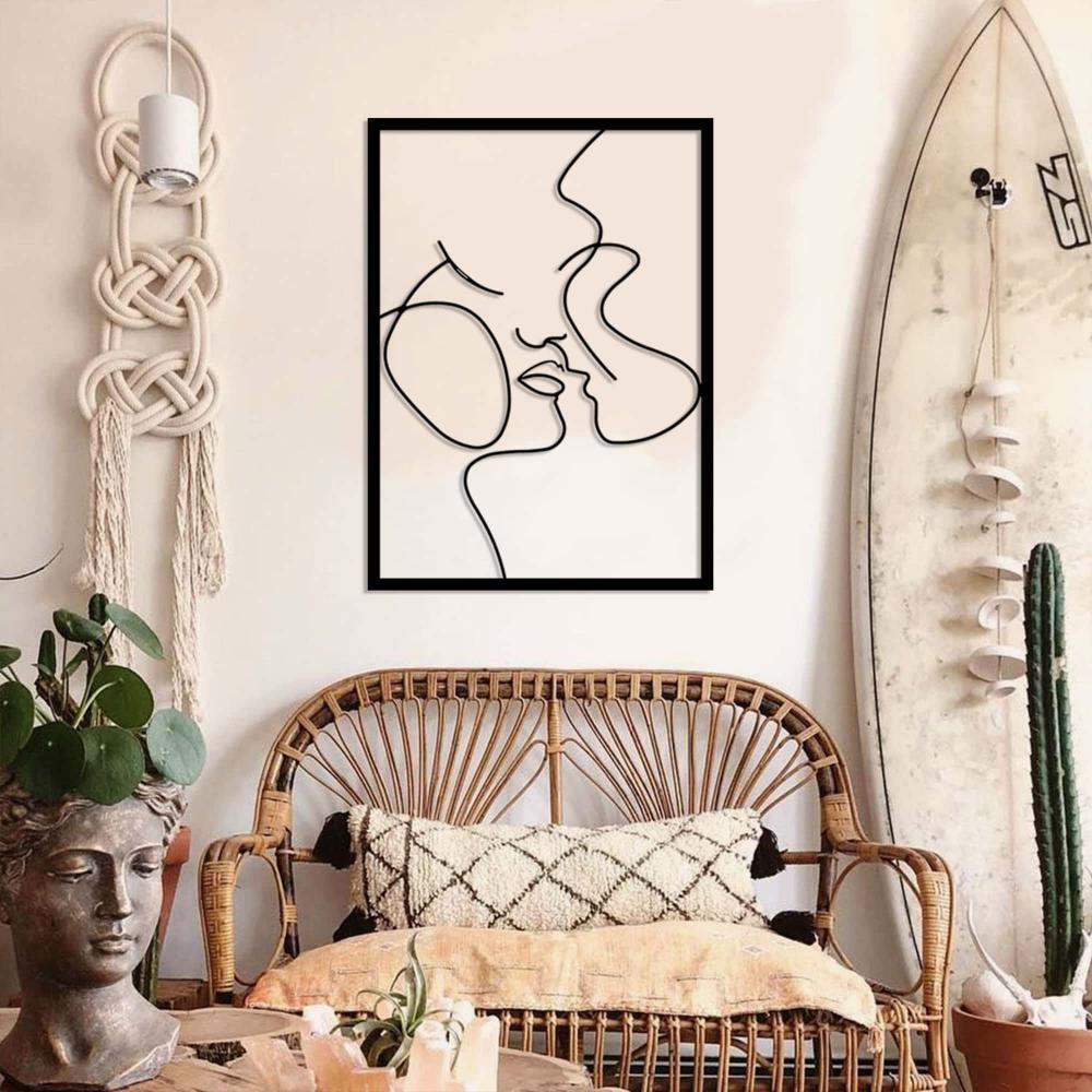 A boho-inspired living room featuring a wicker sofa, macrame wall hanging, and a surfboard, complemented by a "Relationship Goals" metal wall art showcasing an abstract couple design.