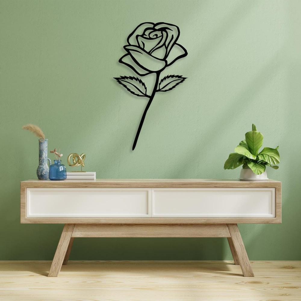 Black rose-shaped metal wall art mounted on a pastel green wall above a light wood and white modern console table. The decor includes a vase, decorative items, and a green potted plant for a serene, stylish ambiance.