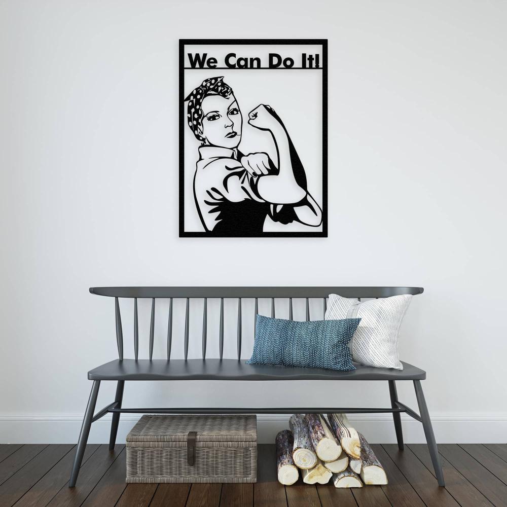 Minimalist room with a black "We Can Do It!" metal wall art featuring Rosie the Riveter above a gray wooden bench, styled with pillows, a wicker basket, and stacked firewood.