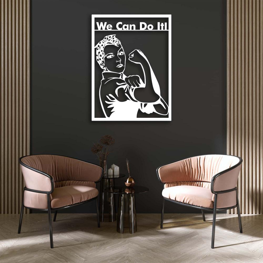 Modern living room with a white "We Can Do It!" metal wall art featuring Rosie the Riveter on a dark green wall, flanked by two blush pink accent chairs and a glass side table.