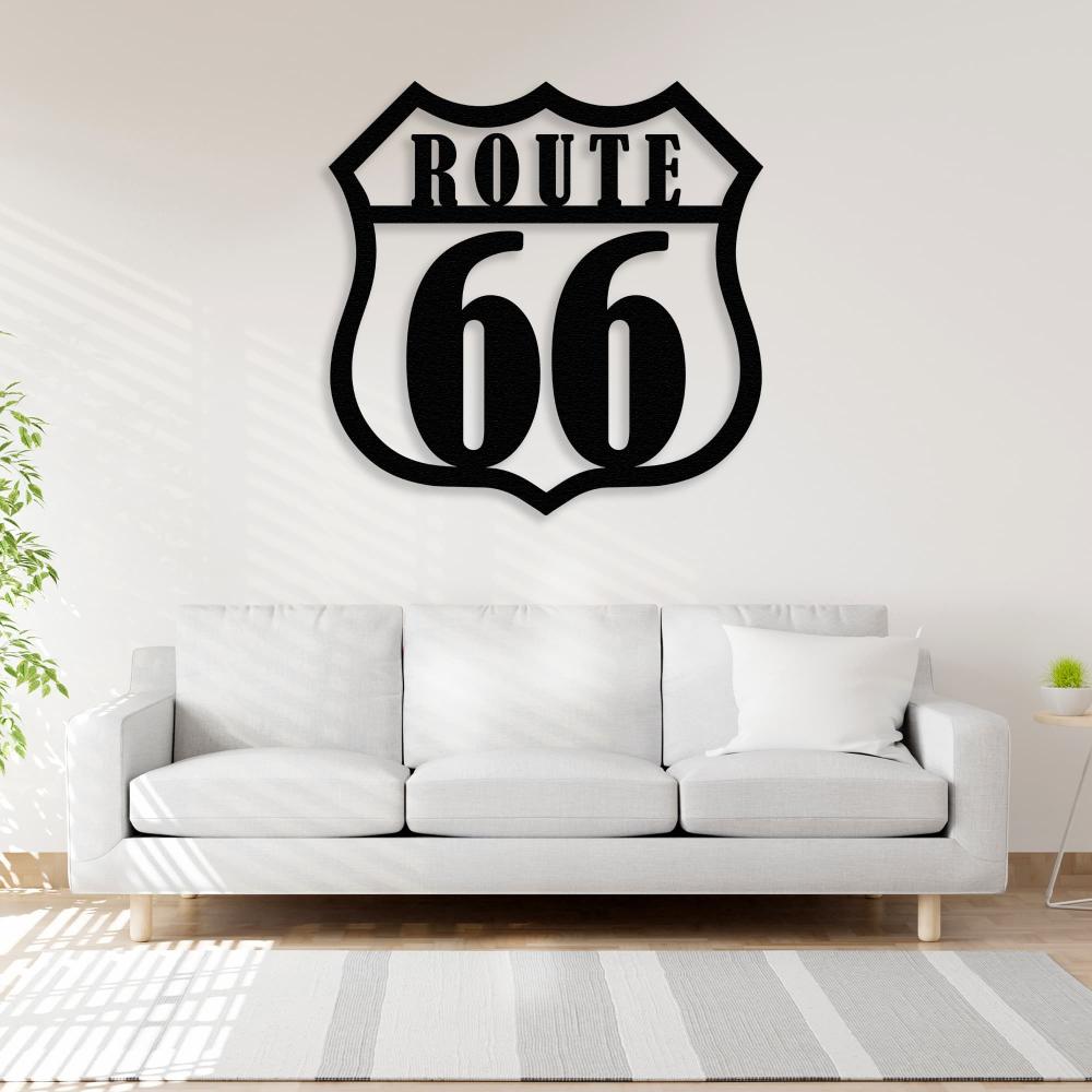 Route 66 metal wall art in black displayed on a light-colored wall above a modern white sofa, with natural sunlight streaming in and a minimalistic indoor plant on the side.