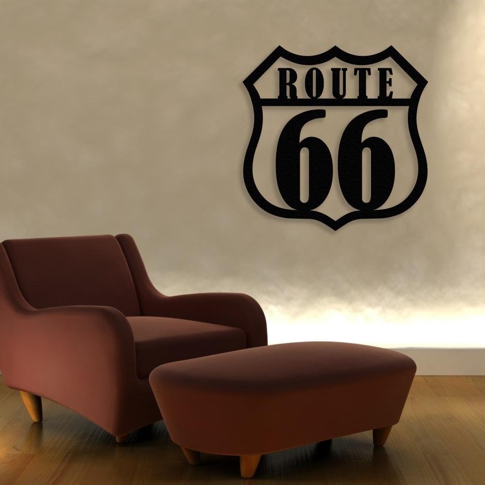 Route 66 black metal wall art mounted on a softly illuminated beige wall, positioned above a retro-style rust-colored armchair and matching ottoman, creating a warm and cozy ambiance.