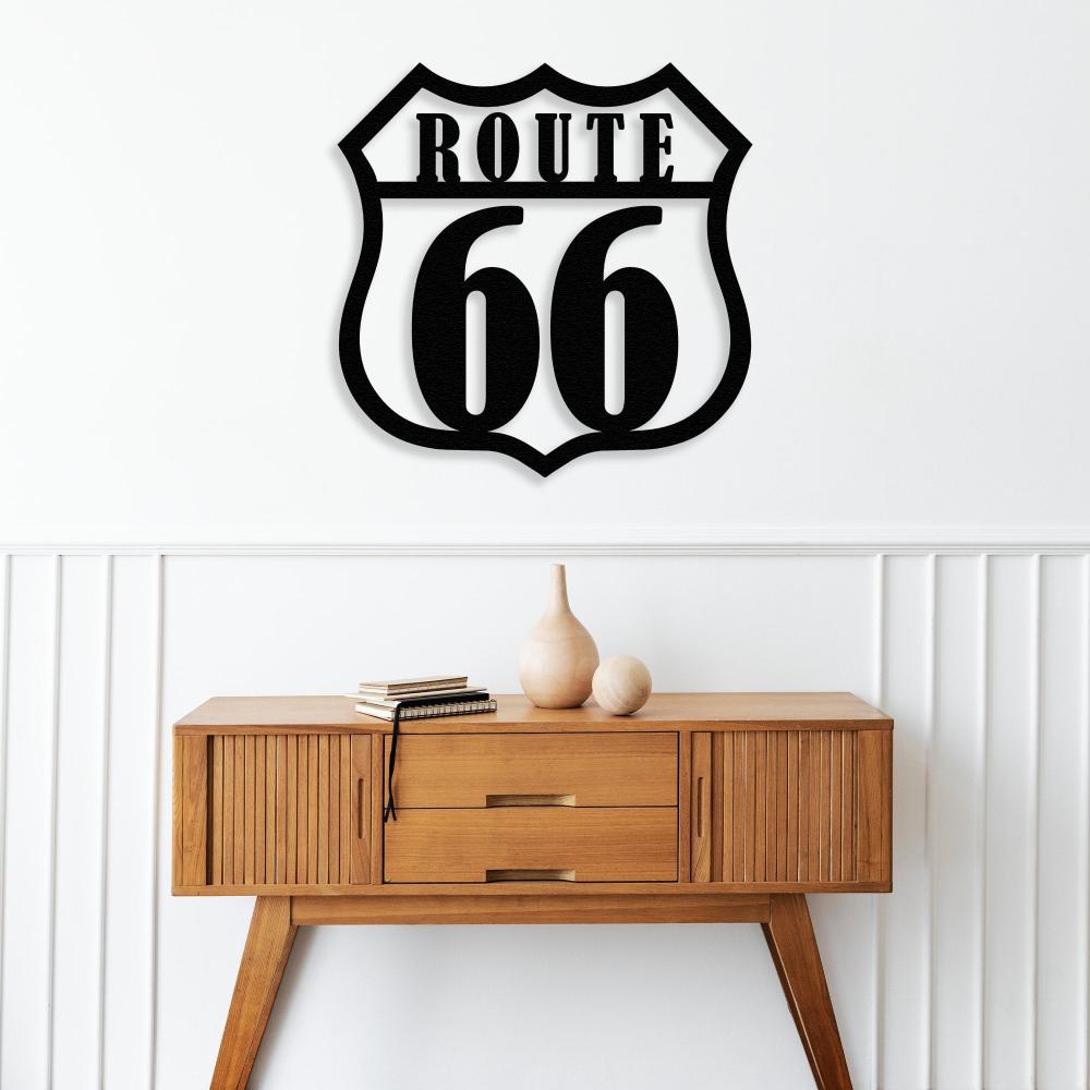 Route 66 black metal wall art mounted on a white wall above a mid-century modern wooden console table decorated with minimalist pottery and stacked books, creating a clean and iconic interior aesthetic.
