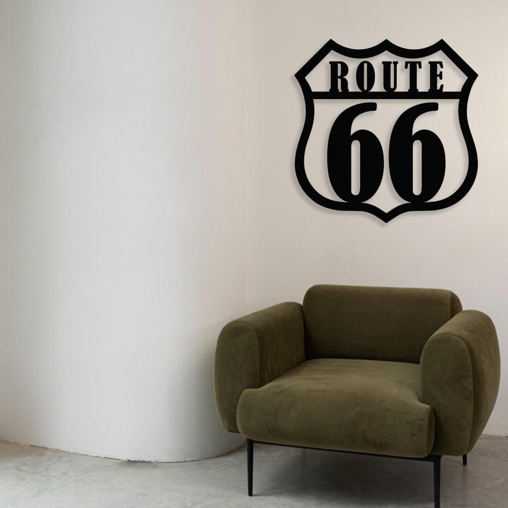 Route 66 metal wall art in black mounted on a plain white wall, positioned above an olive-green modern armchair, adding a vintage Americana vibe to the minimalist decor.