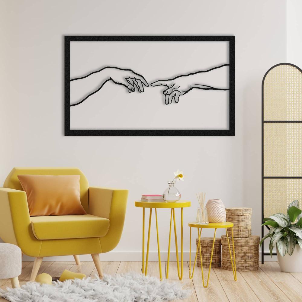 Black metal wall art depicting Michelangelo's "Creation of Adam," mounted on a white wall above a cozy yellow armchair with matching yellow side tables, a fluffy gray rug, and natural wicker decor, creating a harmonious and artistic living space.