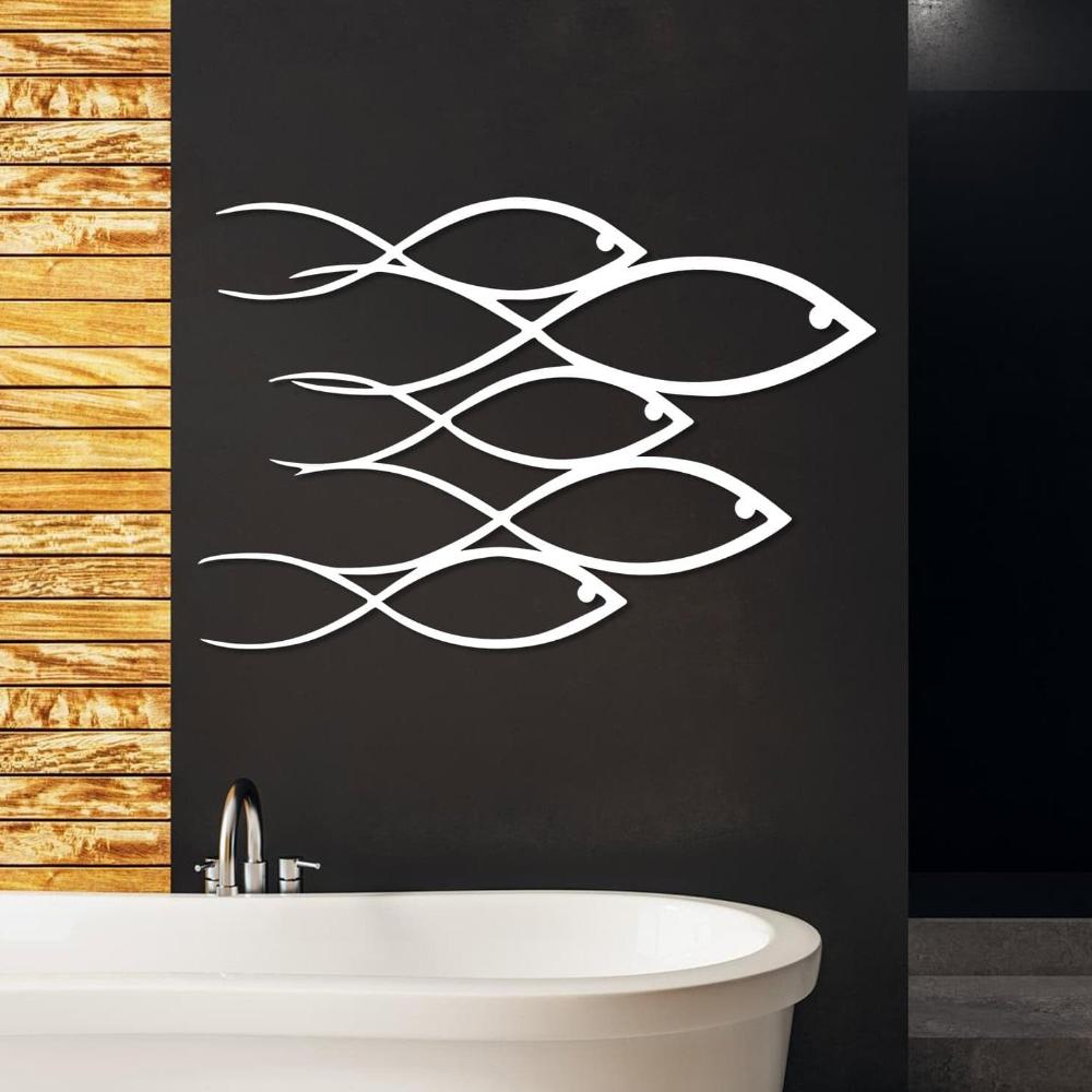 Modern white metal wall art featuring a school of fish design displayed on a dark wall above a freestanding bathtub with wooden panel accents.