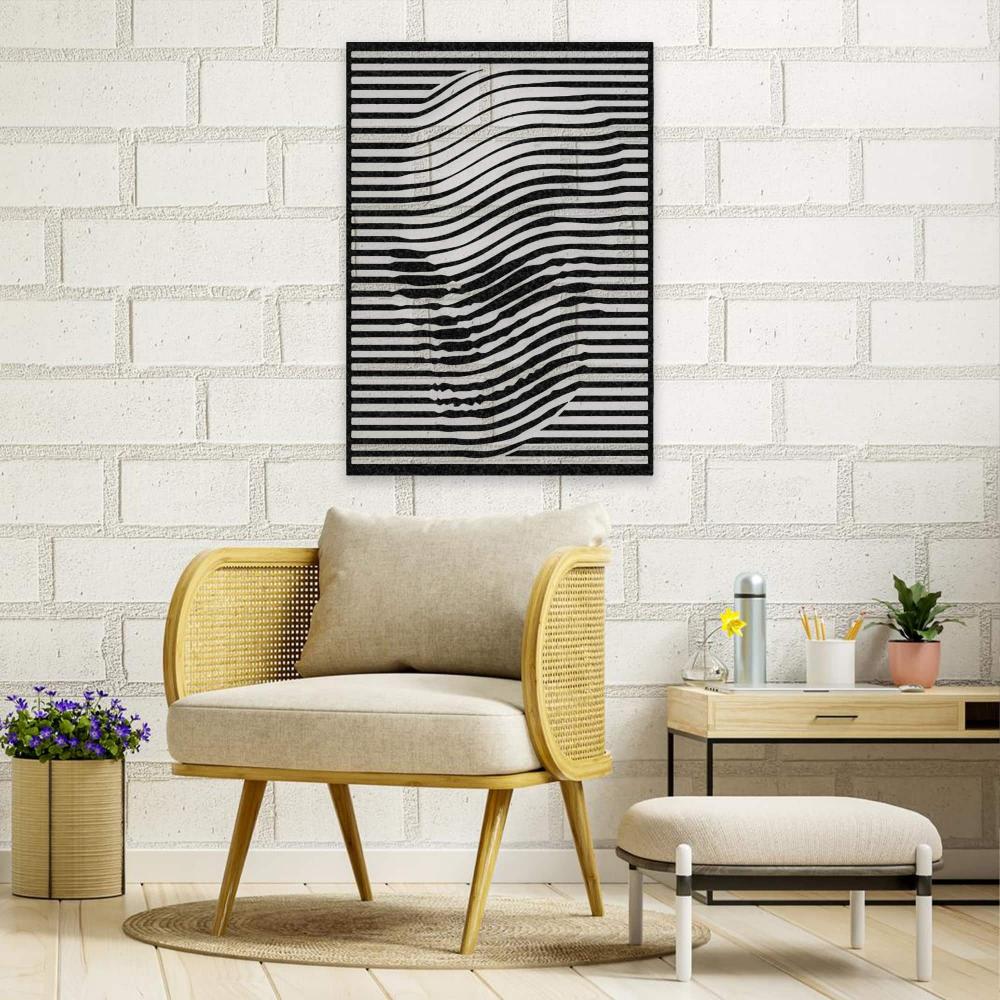 Black skull-themed wall art with abstract wavy lines displayed on a white brick wall, above a beige chair with a matching footrest. The decor includes a side table with plants and stationery, and a vase with purple flowers.