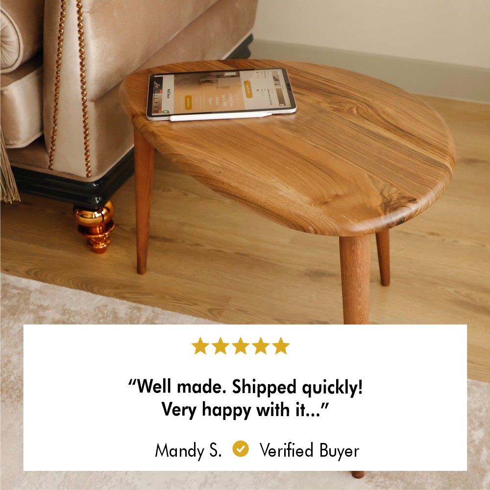 Wooden coffee table with a sleek, rounded design, holding a tablet, positioned on a light beige rug near a couch.
