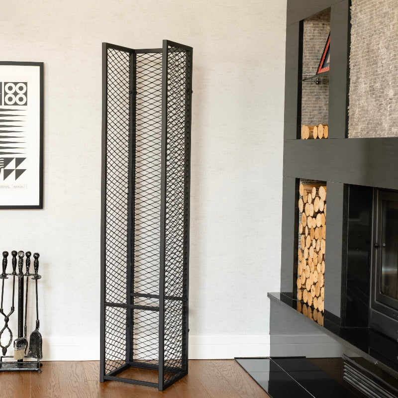 Black wire mesh room divider in a modern living room with a fireplace and decorative elements.