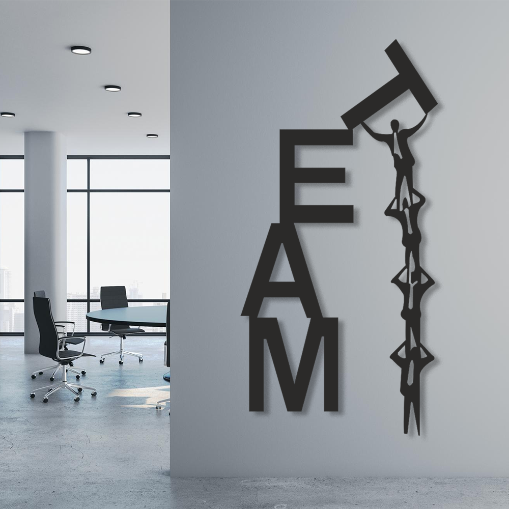 Decorative wall art with 'TEAM' letters and a person climbing on the letter 'M' in an office setting.