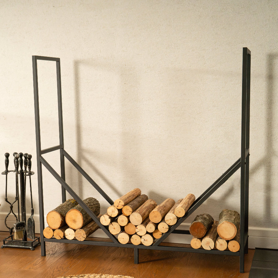 Wooden logs stacked on a metal firewood rack against a plain wall.