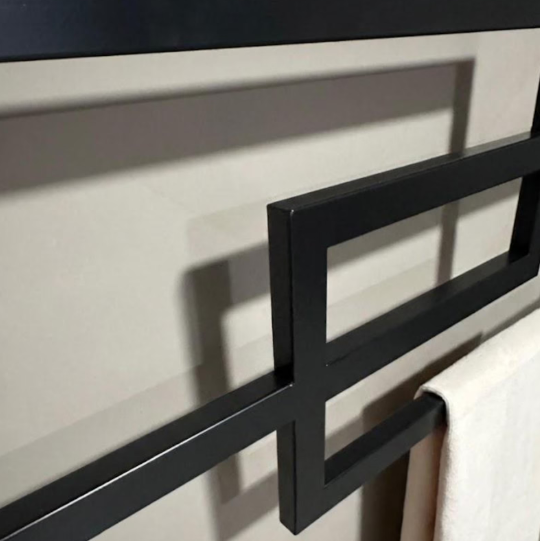 Black metal towel rack on a white wall