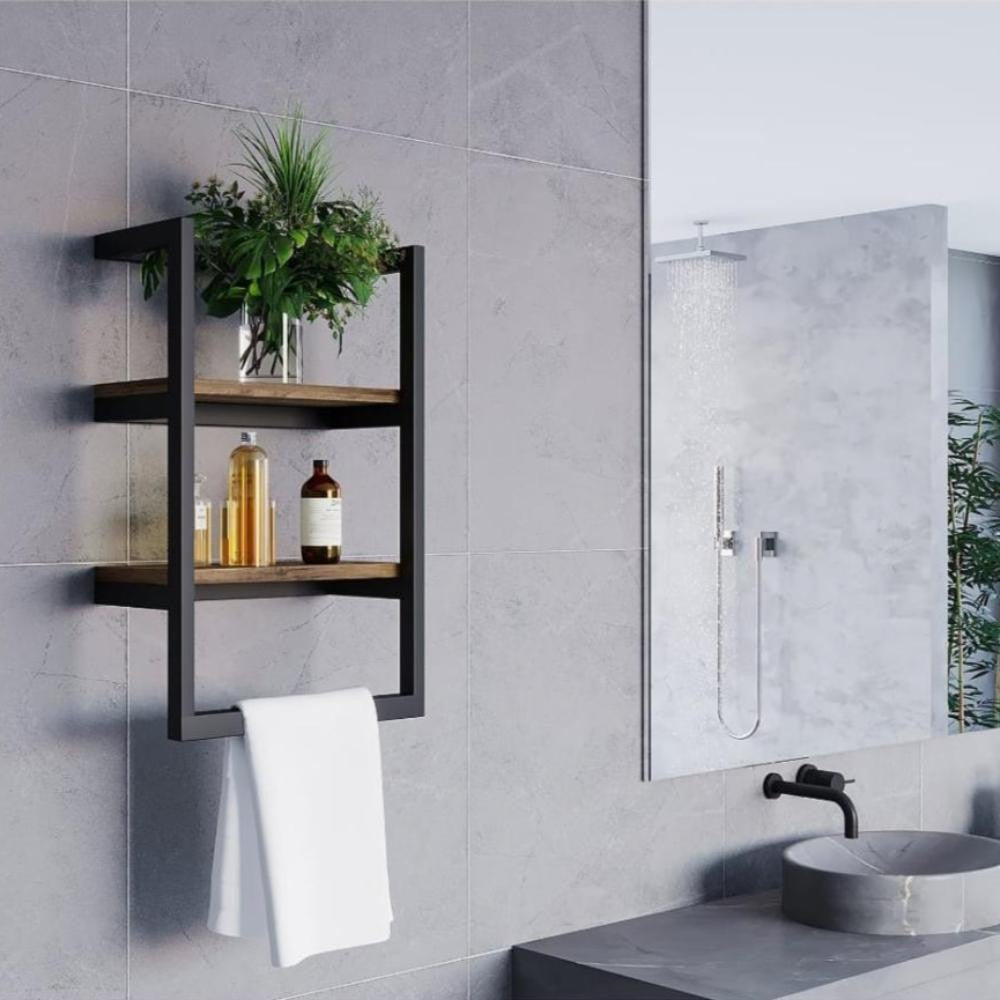 A black wall-mounted shelf with two wooden tiers, featuring a minimalist plant and glass bottle arrangement, placed beside a modern bathroom sink and mirror.