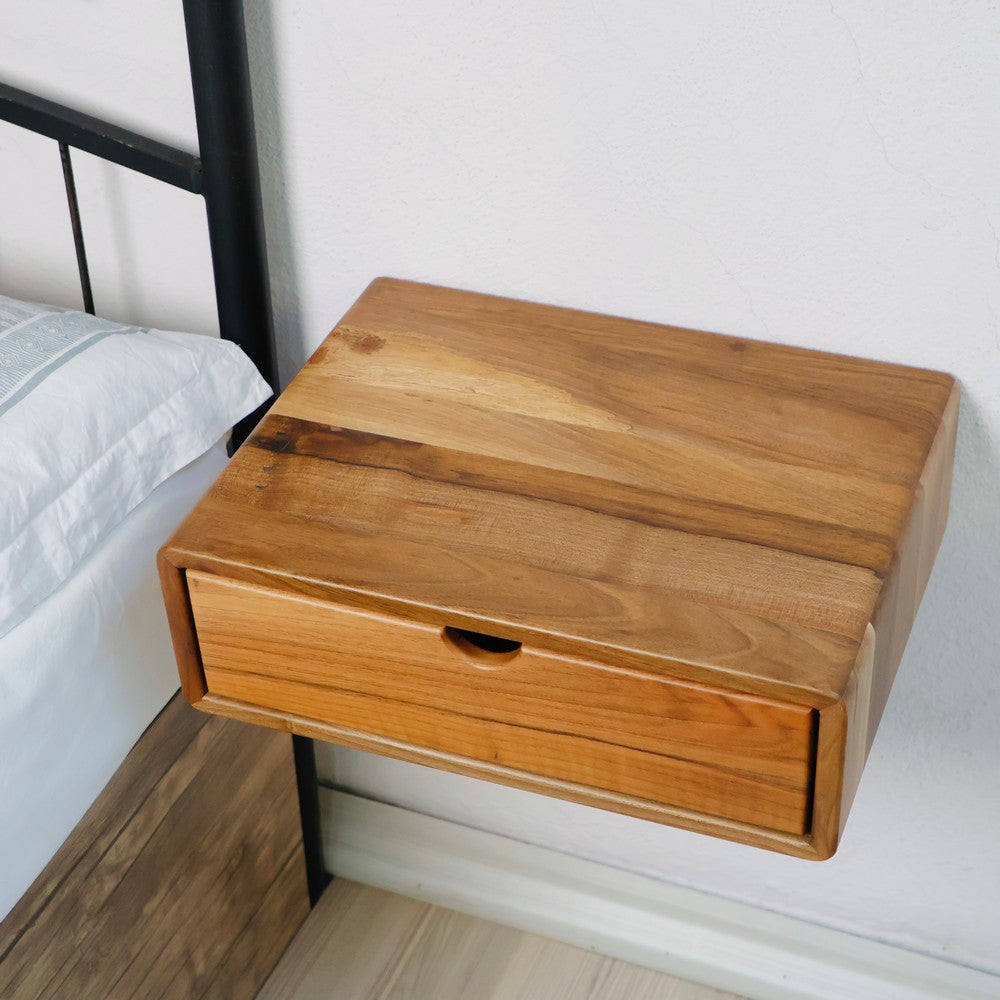 Wall-mounted wooden bedside table with a sleek natural wood finish and a single pull-out drawer. Installed beside a bed, it highlights a minimalist and space-saving design.