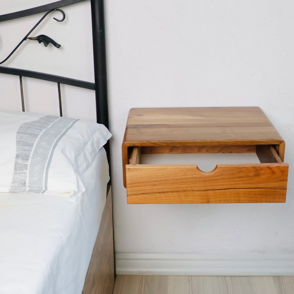 Wall-mounted wooden bedside table with an open drawer showcasing its spacious storage. The smooth natural wood finish adds a warm and modern touch to the minimalist bedroom decor.