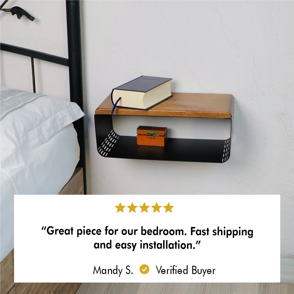 A wall-mounted wooden and metal bedside table with a modern design, featuring a wooden top holding a book and a lower shelf storing a small orange box. A bed with white bedding is partially visible to the left. A five-star review is displayed below, praising the product for its quality, fast shipping, and easy installation, attributed to Mandy S., a verified buyer.