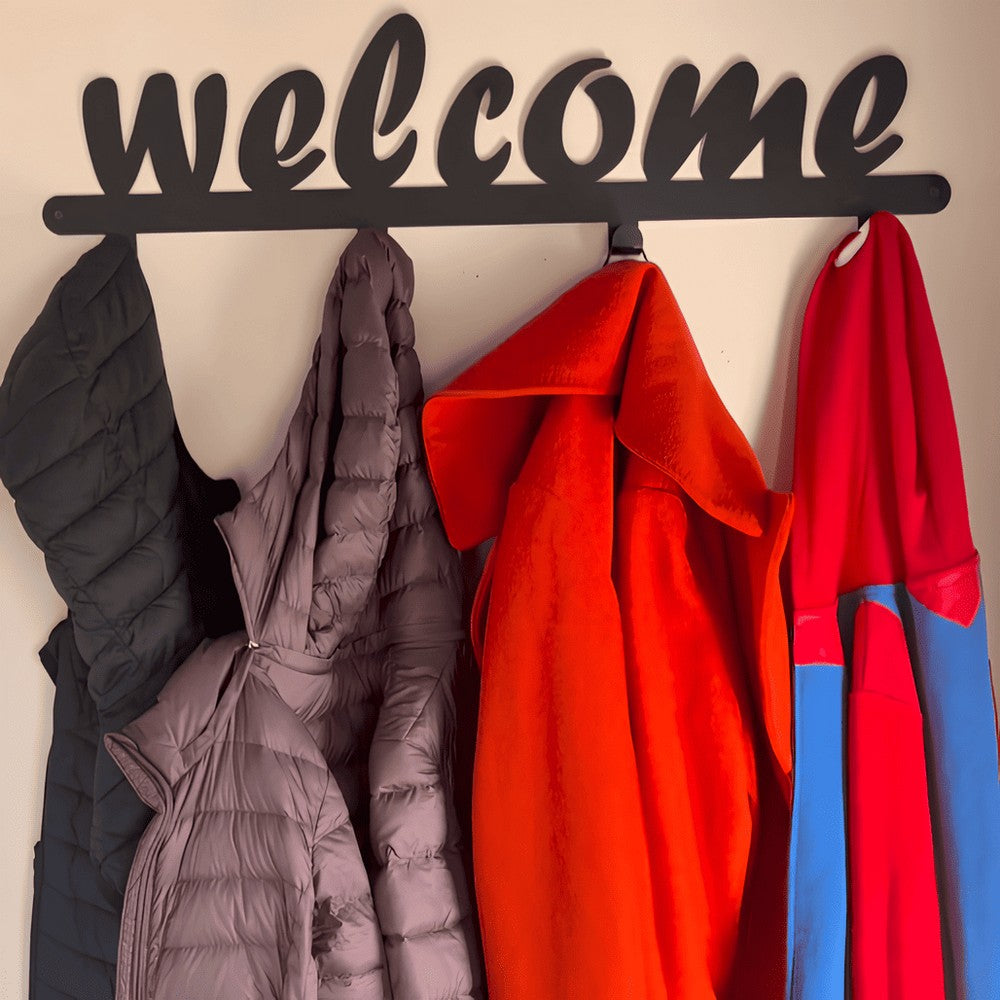 A black metal wall-mounted coat rack featuring the word "welcome" in cursive lettering at the top. The rack has multiple hooks holding various jackets and coats, providing a functional and stylish entryway or hallway accessory. Perfect for organizing coats, hats, and bags while adding a warm and inviting touch to home decor.