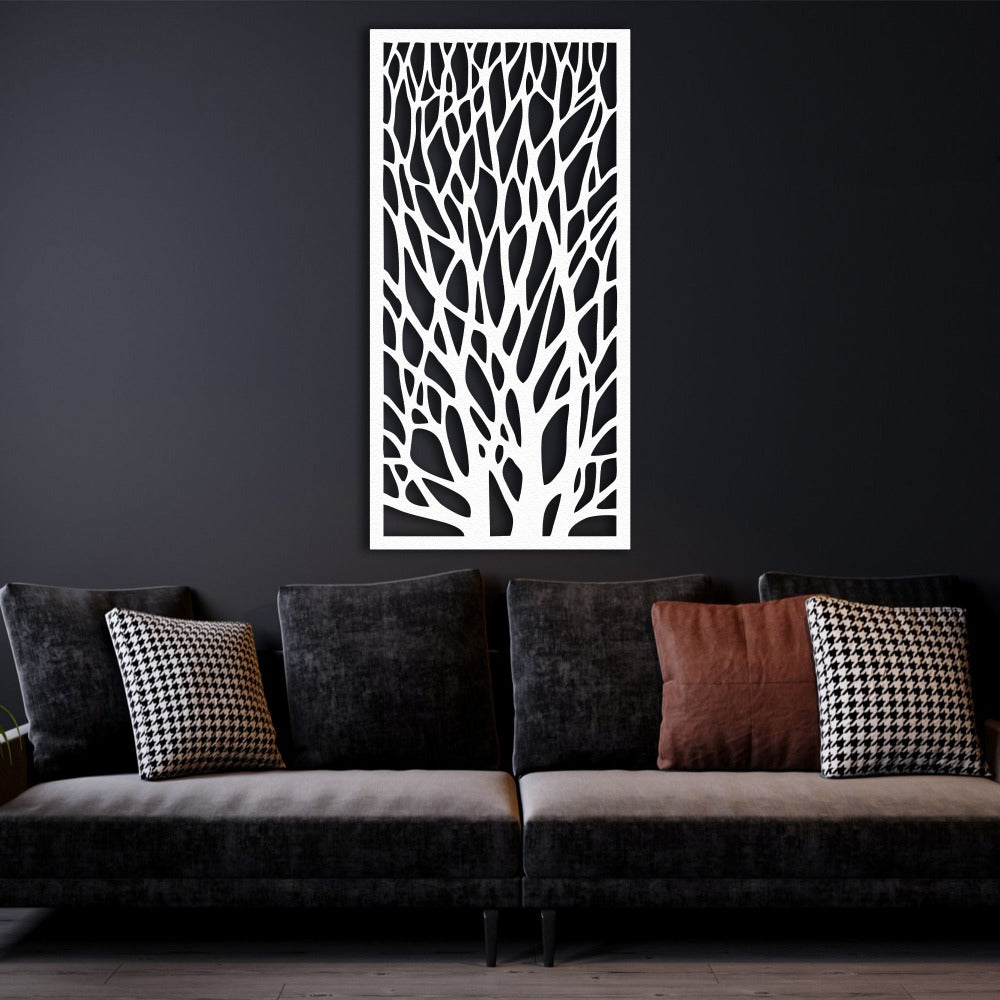 White tree silhouette metal wall art displayed on a dark wall above a modern black sofa with houndstooth-patterned and solid brown throw pillows. The minimalist decor emphasizes the intricate branch pattern of the wall art.