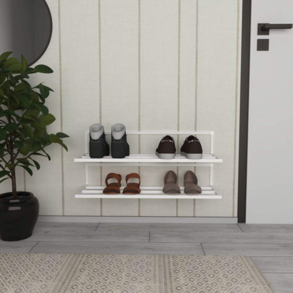 A white wall-mounted shoe rack with two tiers holding boots, sneakers, and heels, placed in an entryway with a potted plant, a circular mirror, and a beige paneled wall.