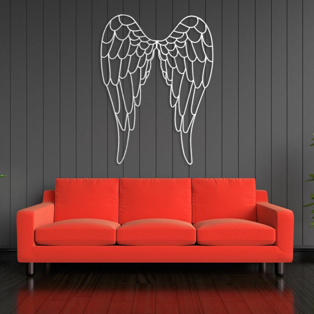 White angel wings metal wall art mounted on a dark paneled wall above a vibrant red sofa, creating a striking contrast and a contemporary decor setting.