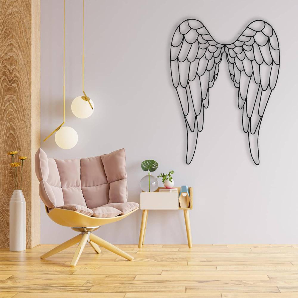 Black angel wings metal wall art displayed on a light wall next to a cozy beige armchair and a small wooden side table with decorative items, adding a serene touch to the modern interior.