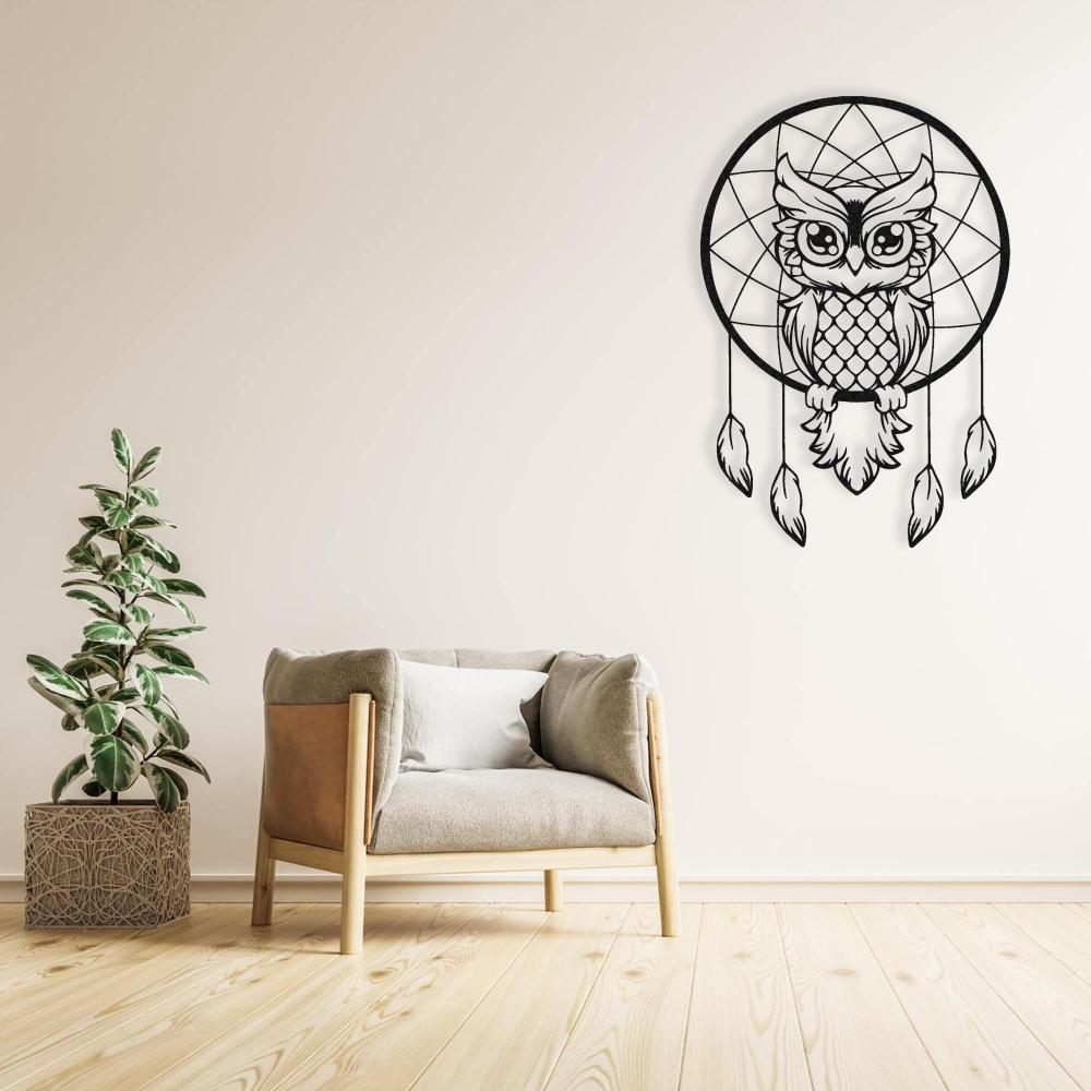 Black metal wall art of a wise owl dreamcatcher styled above a minimalist chair and plant in a modern living room.